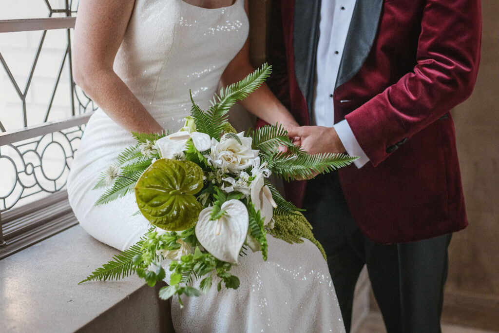 bride and groom holding white and green bouquet with lillies