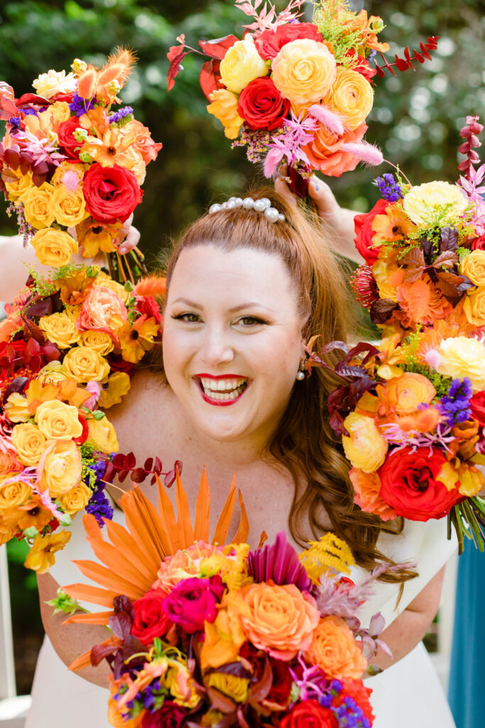 bride surrounded by orange, red, and yellow bouquets of flowers